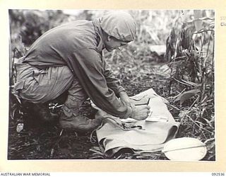 BOUGAINVILLE. 1945-05-24. LIEUTENANT D.F. CHAPLAIN, D COMPANY, 26 INFANTRY BATTALION (AUSTRALIAN IMPERIAL FORCE), CHECKS WITH MAPS BEFORE SETTING OUT ON PATROL AGAINST THE JAPANESE IN THE NORTH ..