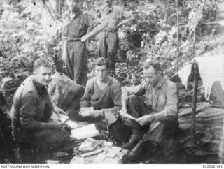 Papua. 1942. Padre McCabe, Salvation Army chaplain (front left), sorts through letters and other papers with the assistance of two soldiers in the Kokoda Flats area. (Original housed in AWM Archive ..