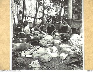 SCARLET BEACH, NEW GUINEA, 1943-10-25. MEMBERS OF THE 2/27TH AUSTRALIAN INFANTRY BATTALION SORTING MAIL, COMPRISING PAPERS AND PARCELS, ON THE SIDE OF THE ROAD, WHICH RUNS THROUGH HOLDSBACK ..
