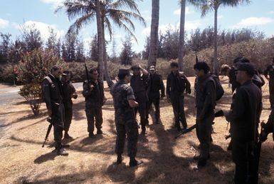 A group of Air Force security police listen as Marine Corps SSGT Dave Gerard critiques the operation they have just completed. The policemen are participating in anti-terrorist training being conducted by the 1ST Marine Brigade School