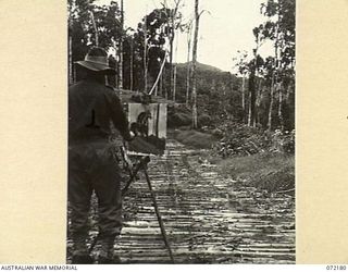 NX191070 LIEUTENANT H. A. HANKE, OFFICIAL WAR ARTIST ATTACHED TO HEADQUARTERS MILITARY HISTORY SECTION, AT HIS EASEL PAINTS THE BACKGROUND FOR A RECONSTRUCTION OF THE 25 POUNDER GUNS OF B TROOP, ..