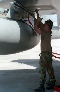 Technical Sergeant (TSGT) Jeffery Reichel (left) and SENIOR AIRMAN (SRA) Jimmy West, both US Air Force (USAF), assigned to the 19TH Fighter Squadron, attach an external fuel tank to the wing pylon of an F-15C Eagle aircraft at Anderson AFB, Guam in support of Exercise TANDEM THRUST '99