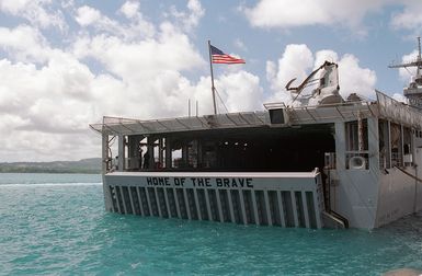 A starboard bow view of the USS FORT MCHENRY (LSD 43) showing the words "HOME OF THE BRAVE" painted on the well deck door, while moored to the Sierra Pier on Guam, during Exercise TANDEM THRUST 99