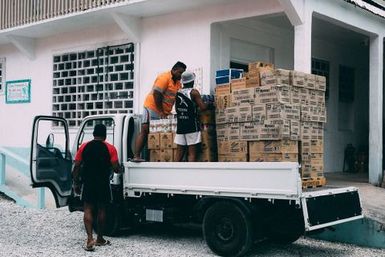 Three men unloading imported goods from a truck, Fakaofo, Tokelau