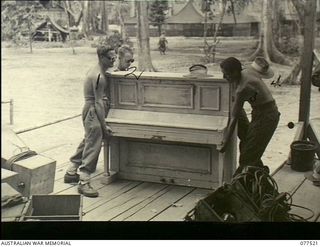 Torokina, Bougainville. 1944-12-07. Members of the Tasmaniacs band with the Tasmania Lines of Communication Area Concert Party moving their piano into position for an evening performance. The men ..