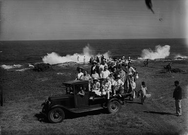 [A group of people watching waves crash against coastline]