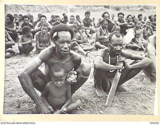 KIARIVU, NEW GUINEA, 1945-08-17. REFUGEE NATIVES LINED UP ON THE AIRSTRIP FOR COUNTING AND INSPECTION BY CAPTAIN R.R. COLE, THE ASSISTANT DISTRICT OFFICER, AUSTRALIAN NEW GUINEA ADMINISTRATIVE ..