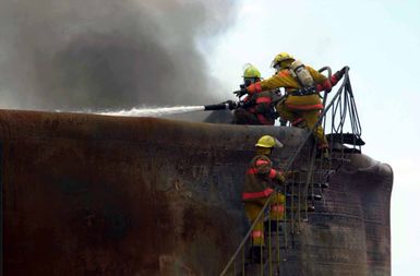 Members of the Guam Fire Department work to extinguish a fuel tank fire in the Cabras Island tank farm