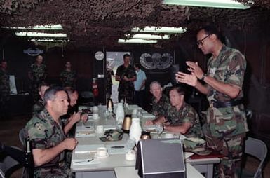 GEN Colin Powell, left, Chairman of the Joint Chiefs of STAFF, sits down for coffee with MGEN Fred A. Gorden, Commanding General, 25th Infantry Division (Light), and other officers during a tour of the division's Light Infantry Training Center