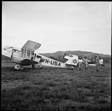 Four people and two bi-planes, one marked VH-USA, New Guinea, ca. 1936 / Sarah Chinnery