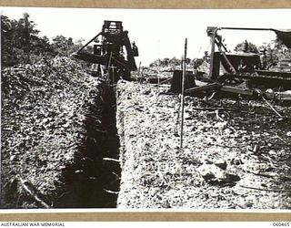 FINSCHHAFEN AREA, NEW GUINEA. 1943-11-09. A TRENCH DIGGING MACHINE OF THE 808TH UNITED STATES ENGINEER AVIATION BATTALION DIGGING AN EXPLORATORY TRENCH THROUGH A CORAL DEPOSIT IN AN EFFORT TO FIND ..