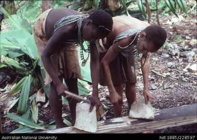 Girls felting bark by beating it with short black-palm clubs