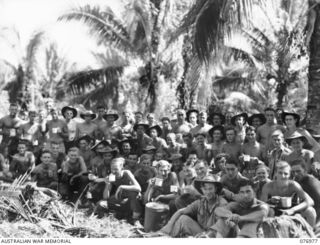 Group portrait of fifty nine personnel of the 472nd Heavy Anti Aircraft Troop enjoying a cup of morning tea while installing their guns in the Wunung Plantation. Identified: VX148064 Gunner (Gnr) ..