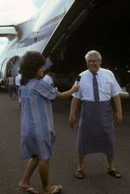 Somoan Governor A.P. Lutali is interviewed by a local television news reporter behind the tail of a 22nd Military Airlift Squadron C-5 Galaxy aircraft. Lutali is at the Pago Pago International Airport to observe the arrival of an emergency electrical generator