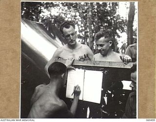 FINSCHHAFEN AREA, NEW GUINEA. 1943-11-13. VX10725 STAFF SERGEANT B. E. SEGAL OF HEADQUARERS, 9TH AUSTRALIAN DIVSION MARKING THE NAMES OF DRAWERS OF HORSES IN THE MELBOURNE CUP SWEEP, AS THEY ARE ..