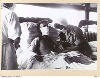 BOUGAINVILLE, 1945-06-18. PTE D. SMITHSON, 11 FIELD AMBULANCE (1), HAVING HIS WOUNDS DRESSED BY SISTER M.M. MCINNES (2) IN THE SURGICAL WARD AT 109 CASUALTY CLEARING STATION