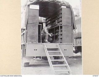 NORTH ALEXISHAFEN, NEW GUINEA. 1944-09-14. NX110641 CORPORAL J. BARNES, STOREMAN, 133RD BRIGADE ORDNANCE FIELD PARK WORKING IN ONE OF THE MOBILE STORES TRUCKS CONTAINING JEEP SPARE PARTS