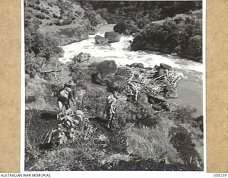 LALOKI VALLEY, NEW GUINEA, 1943-11-05. A PATROL OF THE NEW GUINEA FORCE TRAINING SCHOOL (JUNGLE WING) AT THE EDGE OF THE LALOKI RIVER NEAR THE ROUNA FALLS