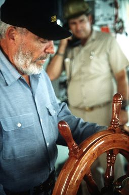 The interior of the pilot house on the missile range instrumentation ship USNS OBSERVATION ISLAND (T-AGM 23) with the helmsman at the wheel