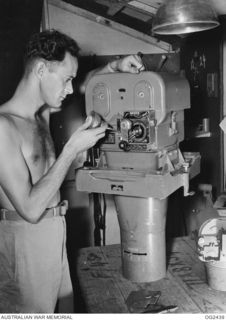 TOROKINA, BOUGAINVILLE ISLAND, SOLOMON ISLANDS. 1945-04-11. 18921 WARRANT OFFICER J. QUIN (?QUINN) OF PRESTON, VIC, OILS THE MECHANISM OF THE GEAR BOX OF A COMPLETE AERIAL CAMERA AS PART OF THE ..