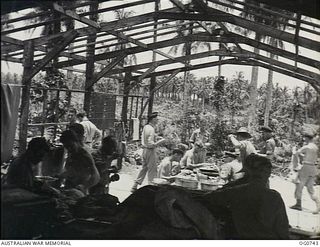 MOMOTE, LOS NEGROS ISLAND, ADMIRALTY ISLANDS. 1944-03-08. RAAF KITTYHAWK PILOTS HAVING THEIR LUNCH AT BENCHES AND TABLES IN A PARTLY ERECTED CREW-ROOM NEAR THE AIRSTRIP. THEY ARE READY TO DROP ..