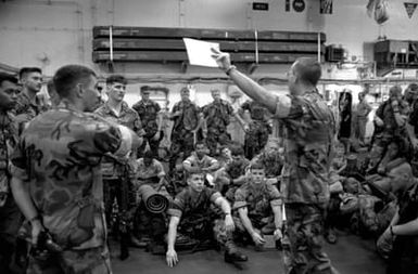 Marines of the 22nd Marine Expeditionary Unit (22nd MEU) gather in the hangar bay aboard the amphibious assault ship USS SAIPAN (LHA 2) for a briefing on the situation in and around Monrovia, Liberia, and the rules of engagement governing their mission once ashore. The SAIPAN is on station off the coast of Liberia for Operation Sharp Edge