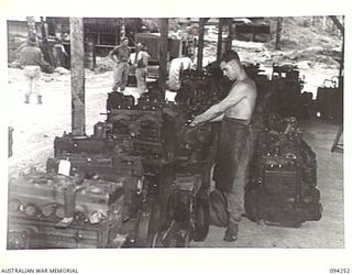 PALMALMAL PLANTATION, NEW BRITAIN. 1945-07-21. CRAFTSMAN J. PERKINS, 1 INFANTRY TROOPS WORKSHOP, STRIPPING DOWN OLD ENGINES WHICH HAVE BEEN REMOVED FROM JEEPS DURING THE RECONDITIONING PROCESS