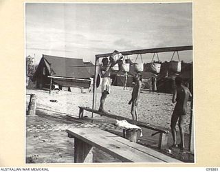 WIRUI BEACH, WEWAK AREA, NEW GUINEA. 1945-08-31. PRIVATE BARTHOLOMEW (1), SERGEANT M.C. ARNOLD (2), AND WARRANT OFFICER 2 C. KEAN (3), MEMBERS OF 2/1 FIELD AMBULANCE AT THE SHOWERS
