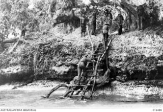 Kapugara Beach, Huon Peninsula, New Guinea. September 1943. Australian troops climbing a Japanese made ladder leading to a rock ledge