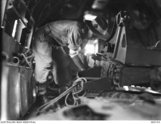 WARD'S DROME, NEW GUINEA. 1943-11-16. NX15067 GUNNER B. G. HOLT OF THE 2/5TH AUSTRALIAN FIELD REGIMENT, 7TH AUSTRALIAN DIVISION, LASHING THE PARTS OF A DISMANTLED LONG 25-POUNDER GUN INTO A DOUGLAS ..