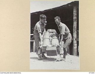 NADZAB, NEW GUINEA. 1944-05-25. VX18127 PRIVATE R ASLETT (1), AND QX6967 PRIVATE P J KEARLEY (2), MEMBERS OF THE 3RD AIR MAINTENANCE COMPANY, CARRYING AN AMERICAN TYPE PARACHUTE ATTACHED TO ..