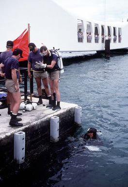 A Navy diver from Mobile Diving Salvage Unit One prepares for a survey dive as tourists watch from the USS ARIZONA (BB-39) Memorial. Members of MDSU One are studying the wreck of the battleship USS ARIZONA (BB-39) as part of Project Sea Mark, a four-year undersea survey and mapping study of naval historic sites. The study is being conducted in conjuction with the U.S. Park Service's Submerged Cultural Resource Unit