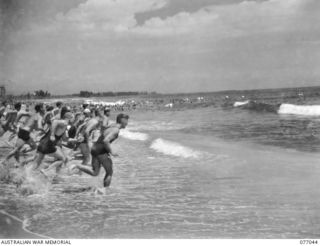 TOROKINA, BOUGAINVILLE, 1944-11-19. ALLIED SERVICE PERSONNEL RACING INTO THE WATER FOR THE START OF THE OPEN SURF RACE AT THE SURF CARNIVAL ORGANISED BY HEADQUARTERS, 3RD DIVISION