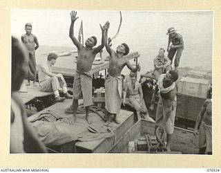 MILFORD HAVEN, LAE, NEW GUINEA. 1944-10-04. TROOPS OF THE 36TH INFANTRY BATTALION AND NATIVES LOADING STORES ABOARD THE DUTCH TROOPSHIP "SWARTENHONDT". IDENTIFIED PERSONNEL ARE:- NX91070 PRIVATE ..