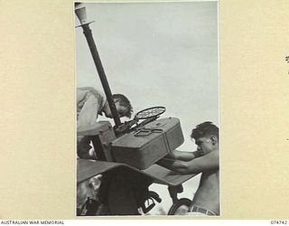 MILILAT, NEW GUINEA. 1944. MEMBERS OF THE CREW OF THE 593RD UNITED STATES BARGE COMPANY COURIER BARGE CHECKING AND INSPECTING THE VESSELS ANTI-AIRCRAFT GUNS DURING THE RUN BETWEEN MADANG AND ..