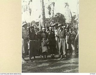 MALAHANG, LAE, NEW GUINEA. 1944-12-25. AUSTRALIAN TROOPS PHOTOGRAPHED WITH NATIVES FROM THE ERAP DISTRICT DURING A NATIVE SING-SING IN THE AUSTRALIAN NEW GUINEA ADMINISTRATIVE UNIT NATIVE COMPOUND