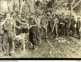 KARKAR ISLAND, NEW GUINEA. 1944-06-02. MEMBERS OF THE 37/52ND INFANTRY BATTALION RECEIVING BISCUITS AND COFFEE ON THE BEACH AT BISON BAY. IDENTIFIED PERSONNEL ARE:- VX108210 PRIVATE S.A. HENSHALL ..