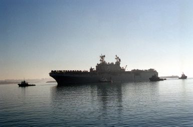 A port side view of the TARAWA CLASS AMPHIBIOUS ASSAULT SHIP USS SAIPAN (LHA 2) as it gets a tow entering the harbor at Naval Station Rota, Spain. The SAIPANS crew will assist in wash-down and inspection of all land vehicles onboard ship during the port visit