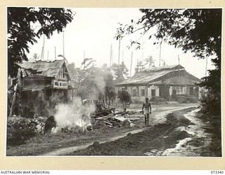 MADANG, NEW GUINEA. 1944-05-18. THE BURNS PHILP SHIPPING COMPANY BUILDING VIEWED APPROXIMATELY 3 WEEKS AFTER ALLIED OCCUPATION, SHOWING THE PARTIAL CLEARANCE OF UNDERGROWTH AND A GOOD ROAD FORMED ..