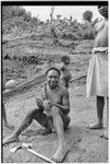 Weaving: man making a belt or armband from plant fibers