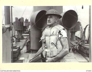 AT SEA, 1944-05-12. MR. J. G. BARNETT (1), A STEWARD ABOARD THE TROOPSHIP ORMISTON, HOLDING A BUCKET WHILE SERVING WITH AN OERLIKON GUN CREW DURING ANTI-AIRCRAFT PRACTICE ON THE VOYAGE FROM PORT ..