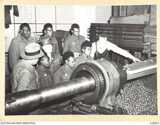 MARIBYRNONG, AUSTRALIA. 1942-10-12. A PARTY OF SIX NATIVE SOLDIERS FROM NEW GUINEA BEING SHOWN OVER THE MUNITION WORKS ARE SEEN WATCHING A HUGE LATHE TURNING A BARREL FOR A BIG GUN