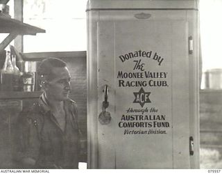 MADANG, NEW GUINEA. 1944-08-29. T255619 CORPORAL H. RUMLEY, COOK, MORESBY BASE SUB-AREA, IS VERY APPRECIATIVE OF THE NEW REFRIGERATOR FROM THE AUSTRALIAN COMFORTS FUND WHICH WAS DONATED BY THE ..