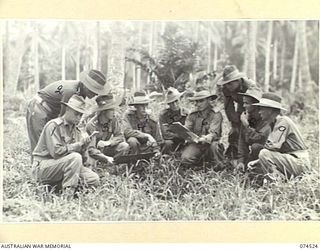 MADANG, NEW GUINEA. 1944-07-07. OFFICERS OF THE 24TH INFANTRY BATTALION LISTENING TO A LECTURE BY THEIR COMMANDING OFFICER IN A CLEARING NEAR THEIR CAMP. IDENTIFIED PERSONNEL ARE:- VX104152 ..