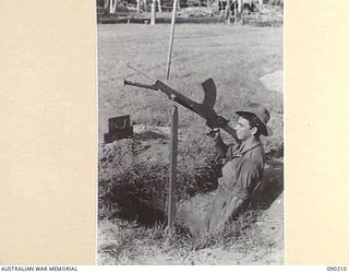 GOODENOUGH ISLAND, NEW GUINEA. 1942-10. AN AUSTRALIAN SOLDIER MANS A DUMMY LIGHT MACHINE GUN. THIS WAS PART OF A MASTERPIECE OF BLUFF AND DECEPTION BY WHICH THE SMALL GROUP OF AUSTRALIANS WHO ..