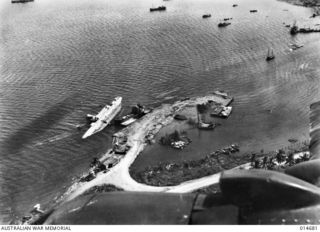 MILNE BAY, NEW GUINEA, 1943-04-16. GILI GILI WHARF SEEN FROM THE AIR, WITH THE CHINESE FREIGHTER ANSHUN LYING ON HER SIDE IN THE SHALLOWS AFTER BEING SUNK BY JAPANESE WARSHIPS