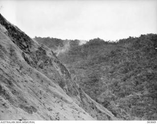 SHAGGY RIDGE, NEW GUINEA. 1944-01-11. A VIEW FROM THE PLATEAU, LOOKING TOWARDS THE JAPANESE POSITION OPPOSITE SHAGGY RIDGE, WHERE SMOKE CAN BE SEEN RISING FROM EXPLODING 25 POUNDER SHELLS. OUR ..
