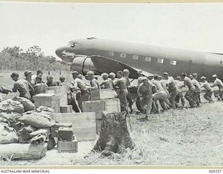 UNITED STATES TROOPS OF THE 32ND UNITED STATES DIVISION DRAGGING THE "SWAMP RAT", A DOUGLAS C47 AIRCRAFT OF THE UNITED STATES 5TH AIR FORCE, OUT OF THE SWAMPY GROUND AT THE END OF THE NEW AIRSTRIP