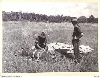 KAHILI, BOUGAINVILLE. 1945-09-10. MEMBERS OF HEADQUARTERS 2 CORPS UNSTRAPPING THE "STORPEDOES" (STORES IN TOPEDO SHAPED CONTAINERS) WHICH HAVE BEEN DROPPED BY PARACHUTE ON THE KAHILI AIRSTRIP FOR ..