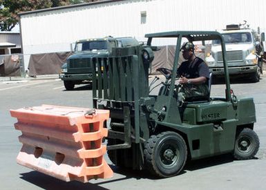 AIRMAN First Class Tommy Hagines, 15th Air Base Wing, Civil Engineering, Hickam Air Force Base, Hawaii, drives a warehouse forklift to move barrier sections from storage to awaiting trucks. The barriers will fortify buildings and control vehicle traffic around the base. Force Protection Condition "Delta" (FP CON Delta) was declared on September 11, 2001 after terrorist attacks on the World Trade Centers Twin Towers in New York and at the Pentagon, when hijackers deliberately flew civilian airliners into the buildings
